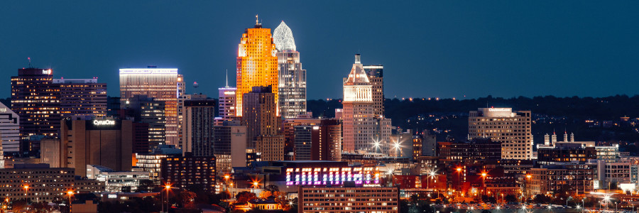 A city skyline glows at night. The word Cincinnati appears on a sign.