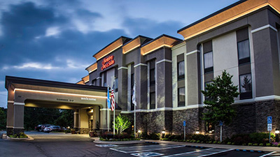 An exterior view of a Hampton Inn entrance in late evening.